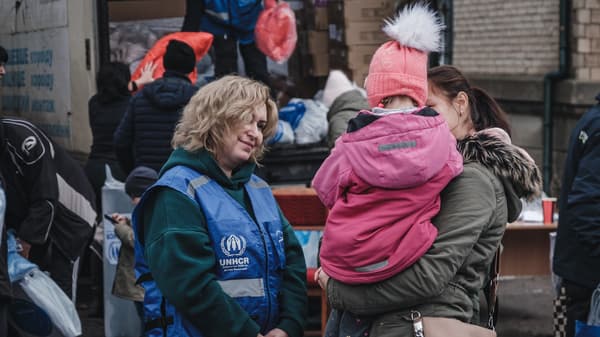 Women with UNHCR clothing and a child in pink jacket