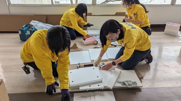 机を組み立てるスタッフ4人。