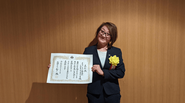 賞状を手に立っているスーツを着た人