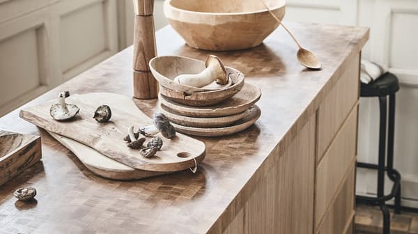 Wooden objects like bowls, a ladle, cutting boards on top of an IKEA SKOGSÅ worktop with a wood surface.