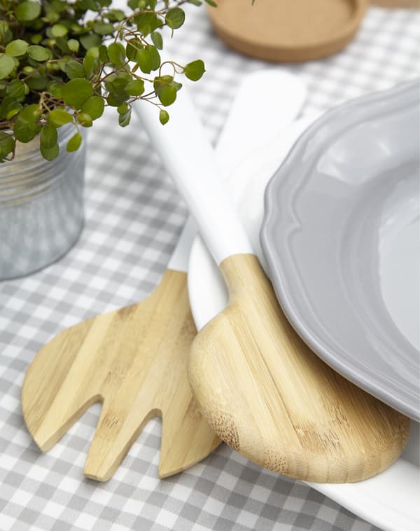 Wooden salad tongs on a table set with grey gingham tablecloth.