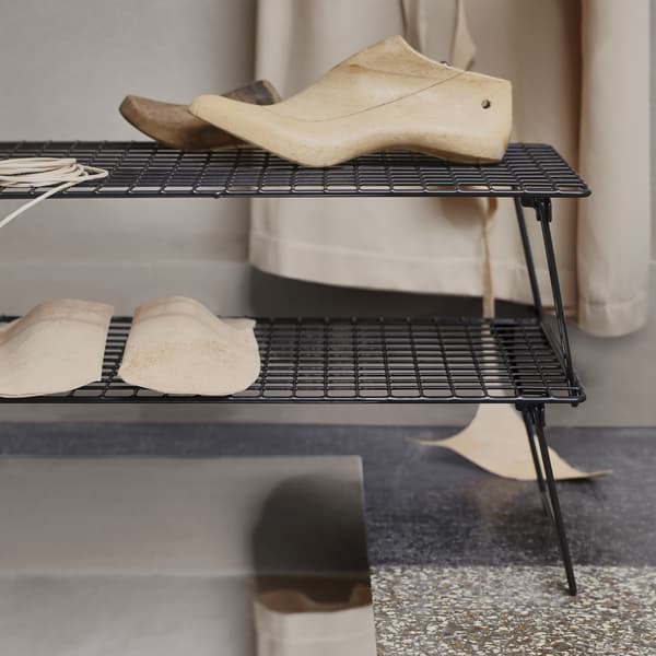 Wooden shoe trees on stacked black shoe racks.