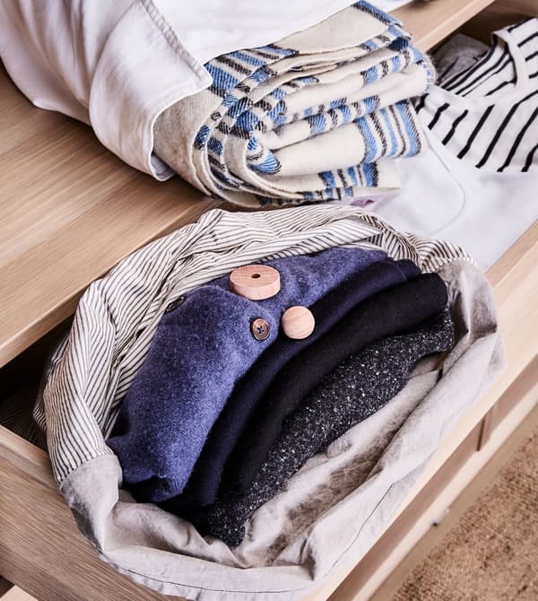 Wool clothing items are folded and placed in cotton bags in drawers.
