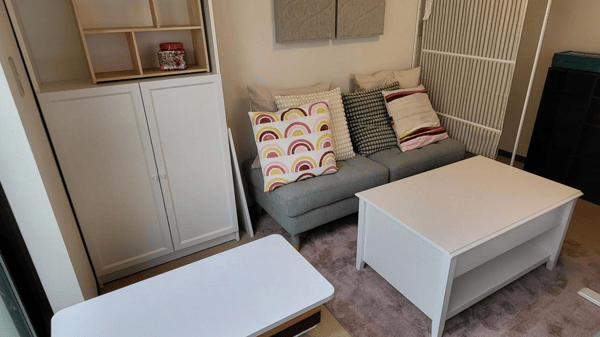 白を基調とした家具とグレーのソファが置かれ、クッションが並んでいる。