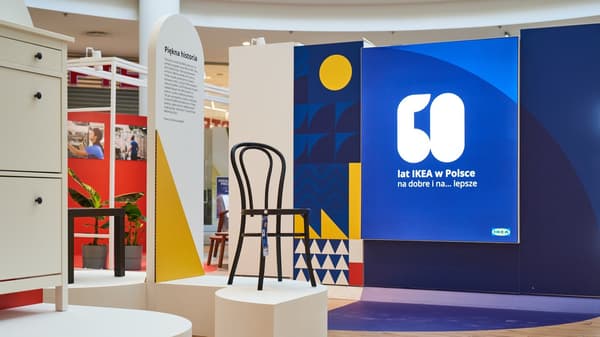 Wystawa IKEA. Na pierwszym planie po lewej stronie stoi szafka na buty. Na środku krzesło OGLA z giętego drewna. W tle elementy konstrucyjne wystawy z opisami i stolikiem LACK. Dalej wielki napis "60 lat IKEA w Polsce. Na dobre i ...na lepsze".