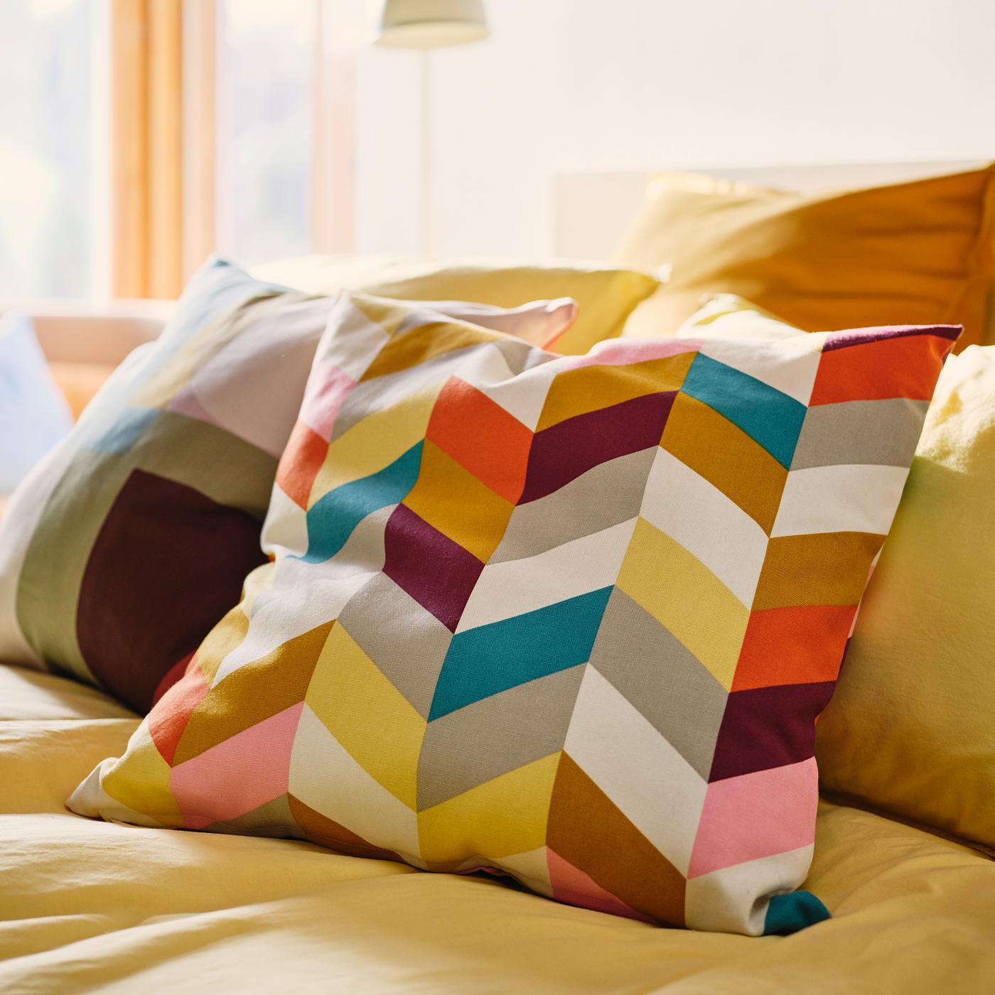 Yellow bed linen, yellow cushions, a multicoloured cushion and a HANNELISE cushion with a bold, colourful pattern.