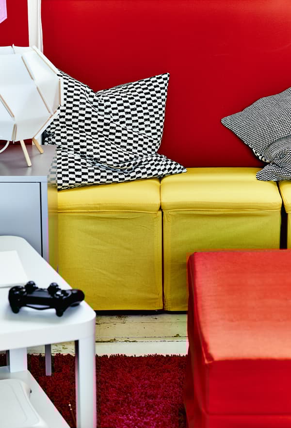 Yellow footstools against a red wall.