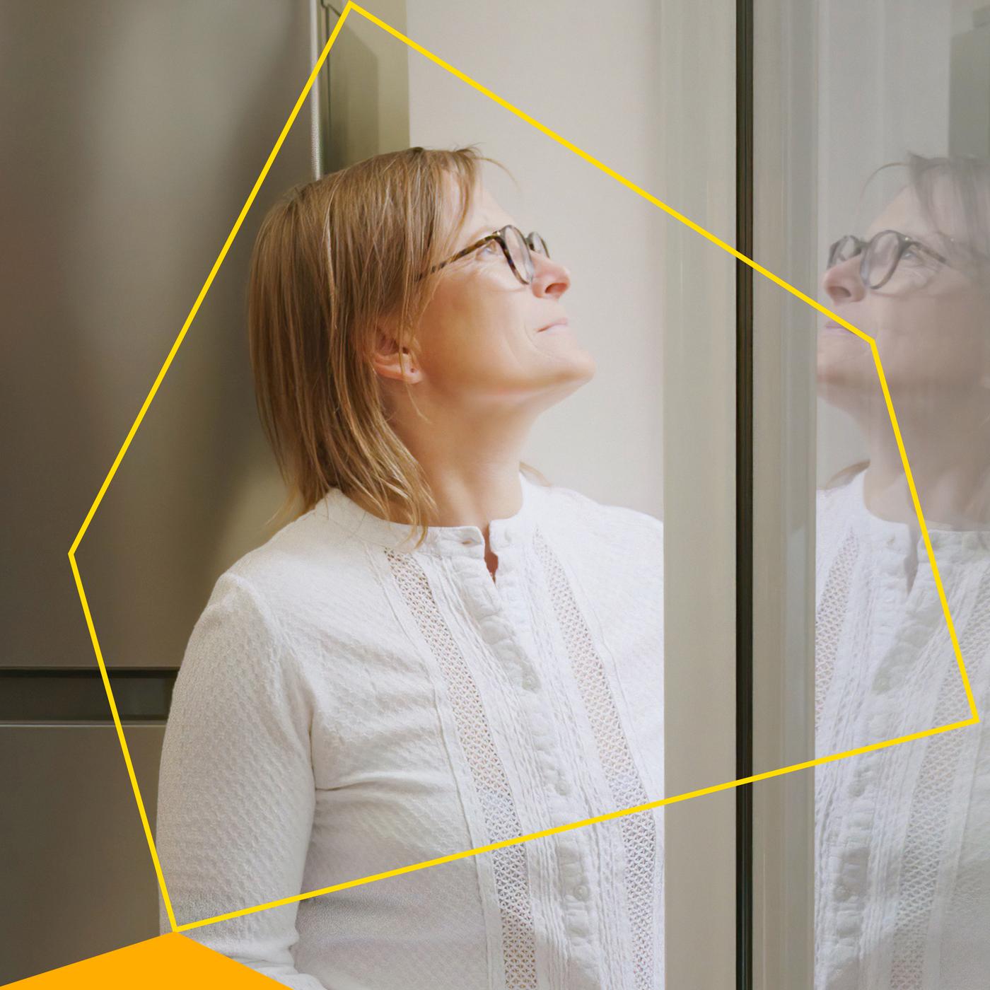 Yellow house-outline graphic appears on a woman looking out her house window.
