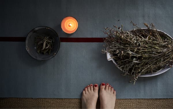Yoga estera, kandela eta belarrez betetako kaikuak.