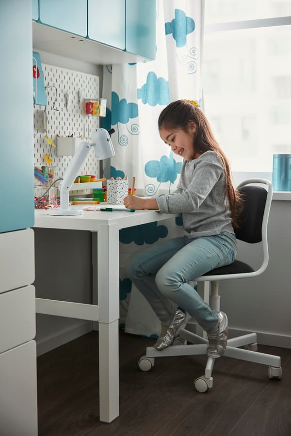 Young girl studying and doing homework at white PAHL desk in a children's room in Singapore