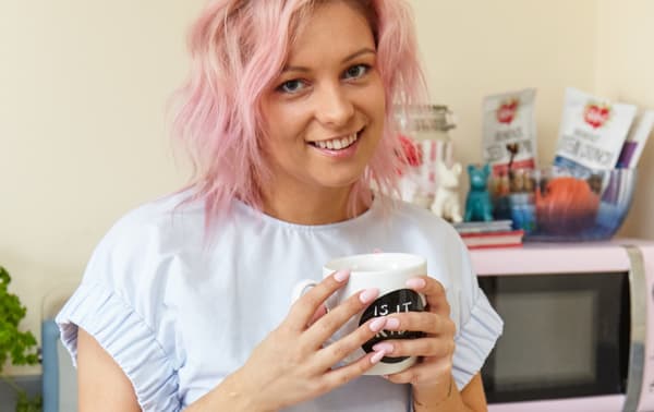 Young woman with pink hair smiling into the camera.