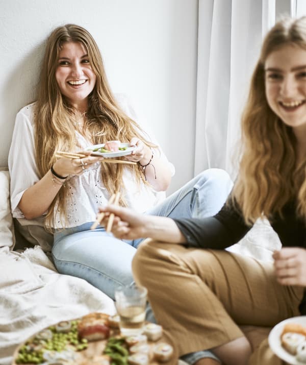 Yvet e i suoi amici seduti attorno a un piatto di sushi sul letto - IKEA