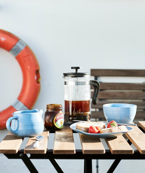 Záhradný stôl prestretý na raňajky a oranžové záchranné koleso v pozadí.