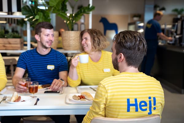 Zaměstnanci IKEA, co vedou konverzaci nad šálkem nápoje a jídlem v zaměstnanecké kantýně. 