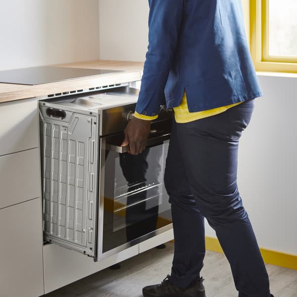 Zaměstnanec IKEA demontuje troubu z kuchyňské linky.