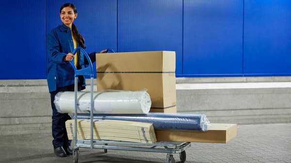 Zamestnanec IKEA s objemnou objednávkou na vozíčku. 
