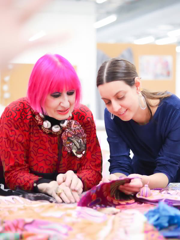 Zandra Rhodes eta IKEA-ko diseinatzaile Paulin Machado mahai baten gainean jarritako ehun koloretsuei begira daude.