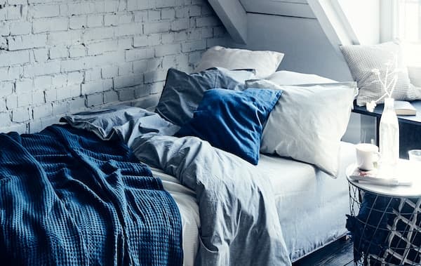 Zariaďte si v obývacej izbe útulnú spálňu pre hostí s rozkladacou pohovkou IKEA GRÄLVIKEN s modro-bielymi posteľnými obliečkami a vankúšmi.