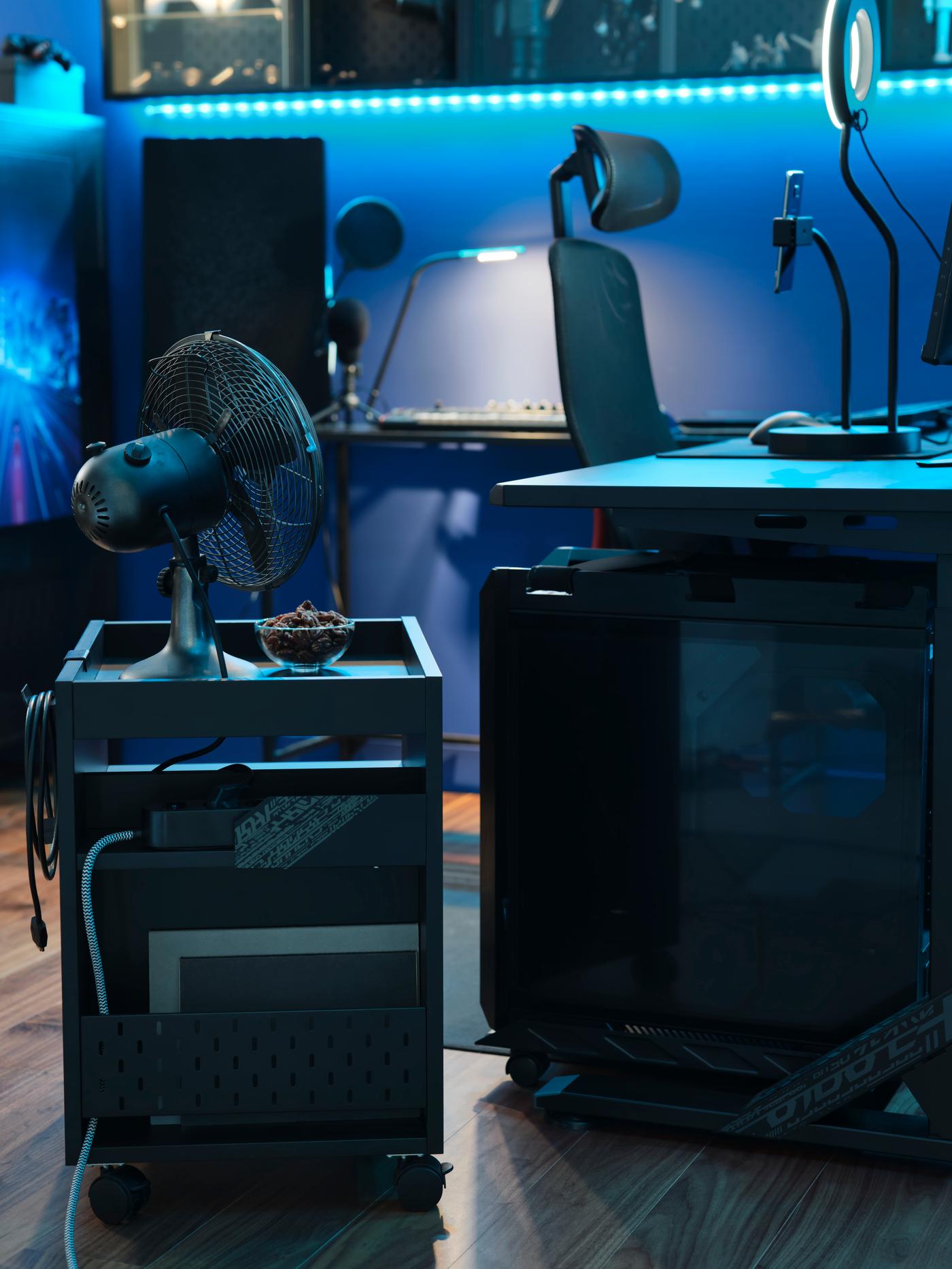 Zásuvková jednotka UPPSPEL na kolečkách v černé barvě. V pozadí židle a stůl pro hráče.