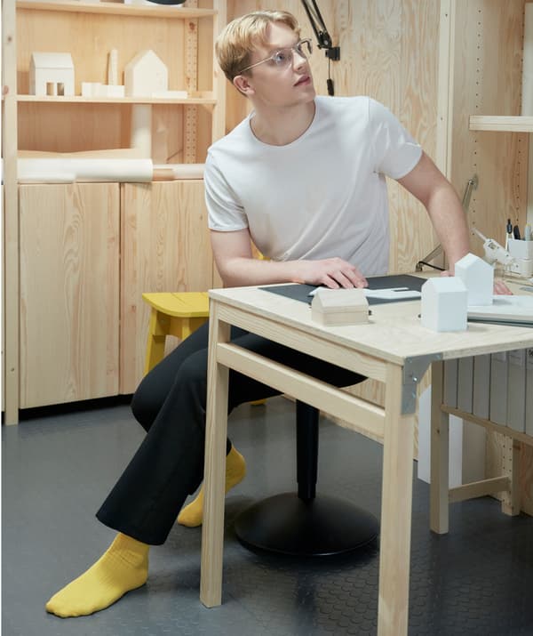 Zatopiony w myślach student siedzi przy biurku, pracując nad projektem.