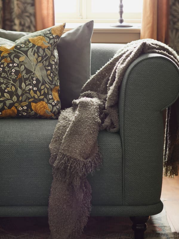 Zelená pohovka VISKAFORS s vankúšom TUVSÄV a zelenohnedou dekou SANDBRODD.