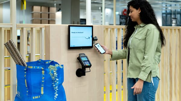 Žena, co chytře platí u pokladny s aplikací IKEA. 