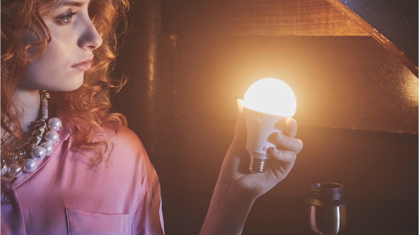 Žena drží v ruce rozsvícenou žárovku.