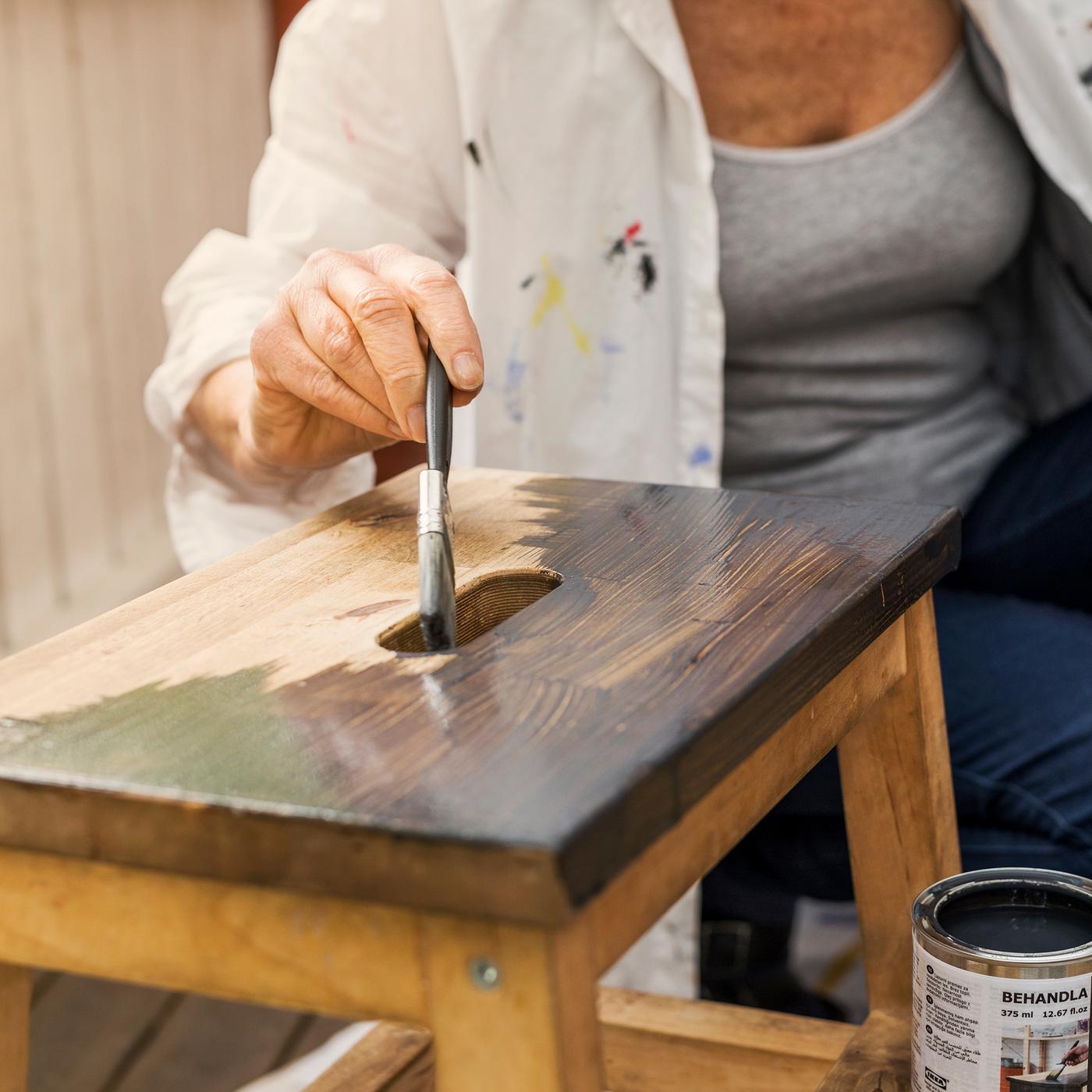 Žena farba stoličicu.