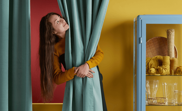 Žena grli zelenu zavesu i oko nje su drugi IKEA proizvodi