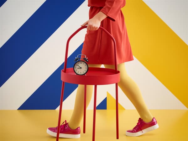 Žena odcházející z IKEA držící žluté schůdky a velký nákup