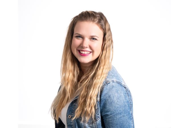 Žena s dlhými vlasmi v denimovej bunde, usmievajúca sa na kameru.