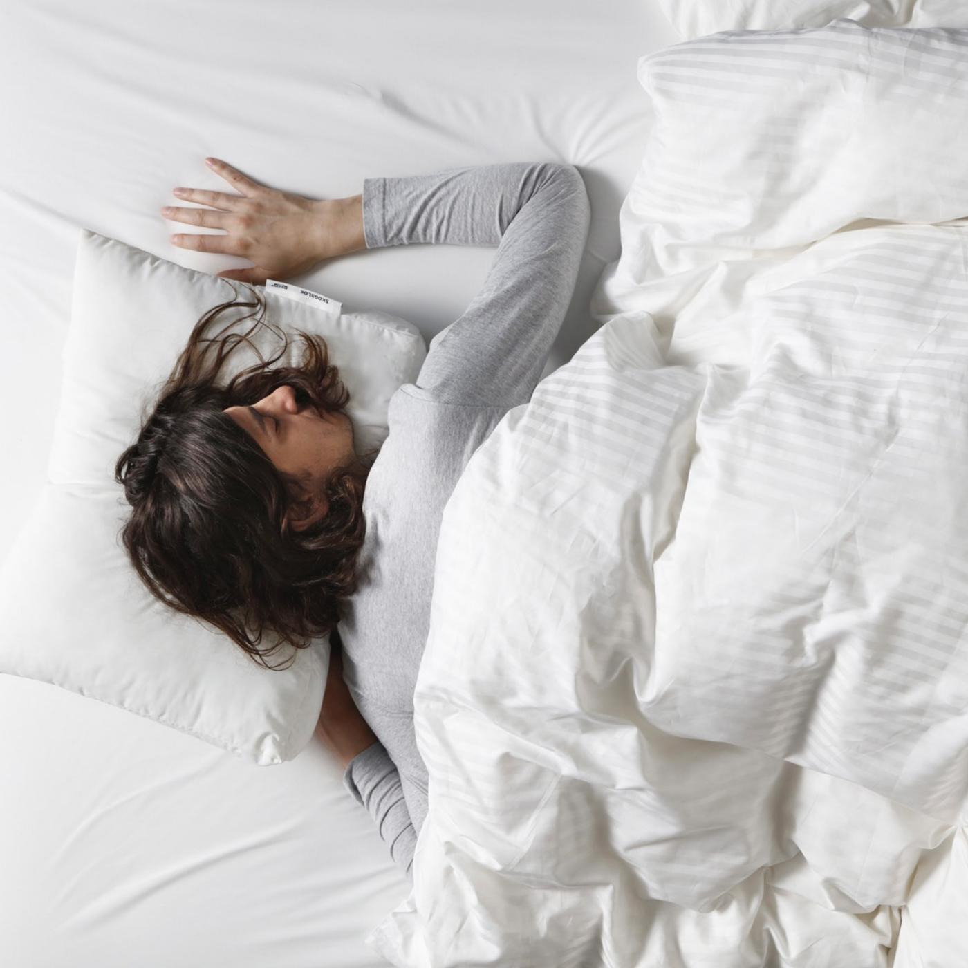 Žena spava na krevetu, na stomaku.