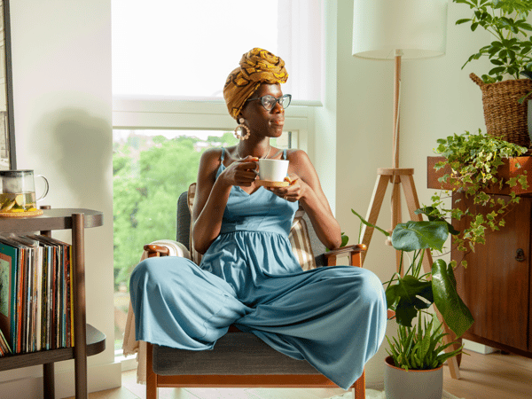 Žena uvoľnene sedí v kresle v a popíja čaj z hrnčeka IKEA 365+.
