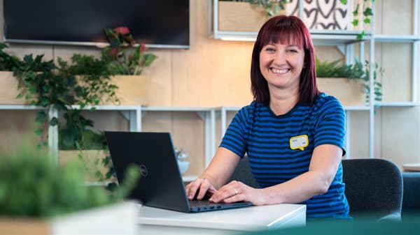 Žena v uniforme IKEA pracuje na počítači za stolom.