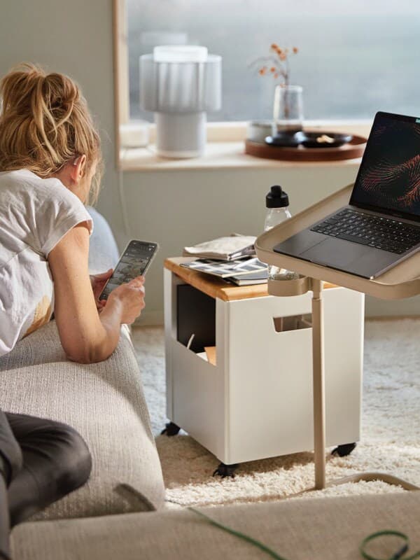 Ženska brska po mobilnem telefonu, medtem ko leži na sedežni garnituri