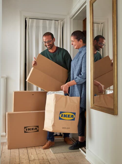 Ženska in moški s paketi in vrečkami iz trgovine IKEA.