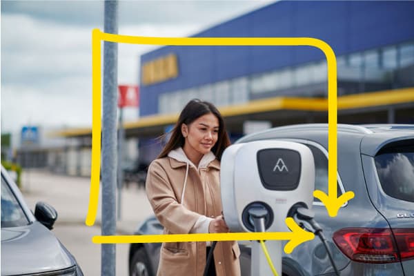Ženska na parkirišču IKEA polni svoj električni avtomobil.