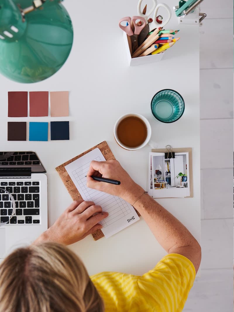 Ženska si zapisuje podatke, ob njej je računalnik in barvna lestvica.