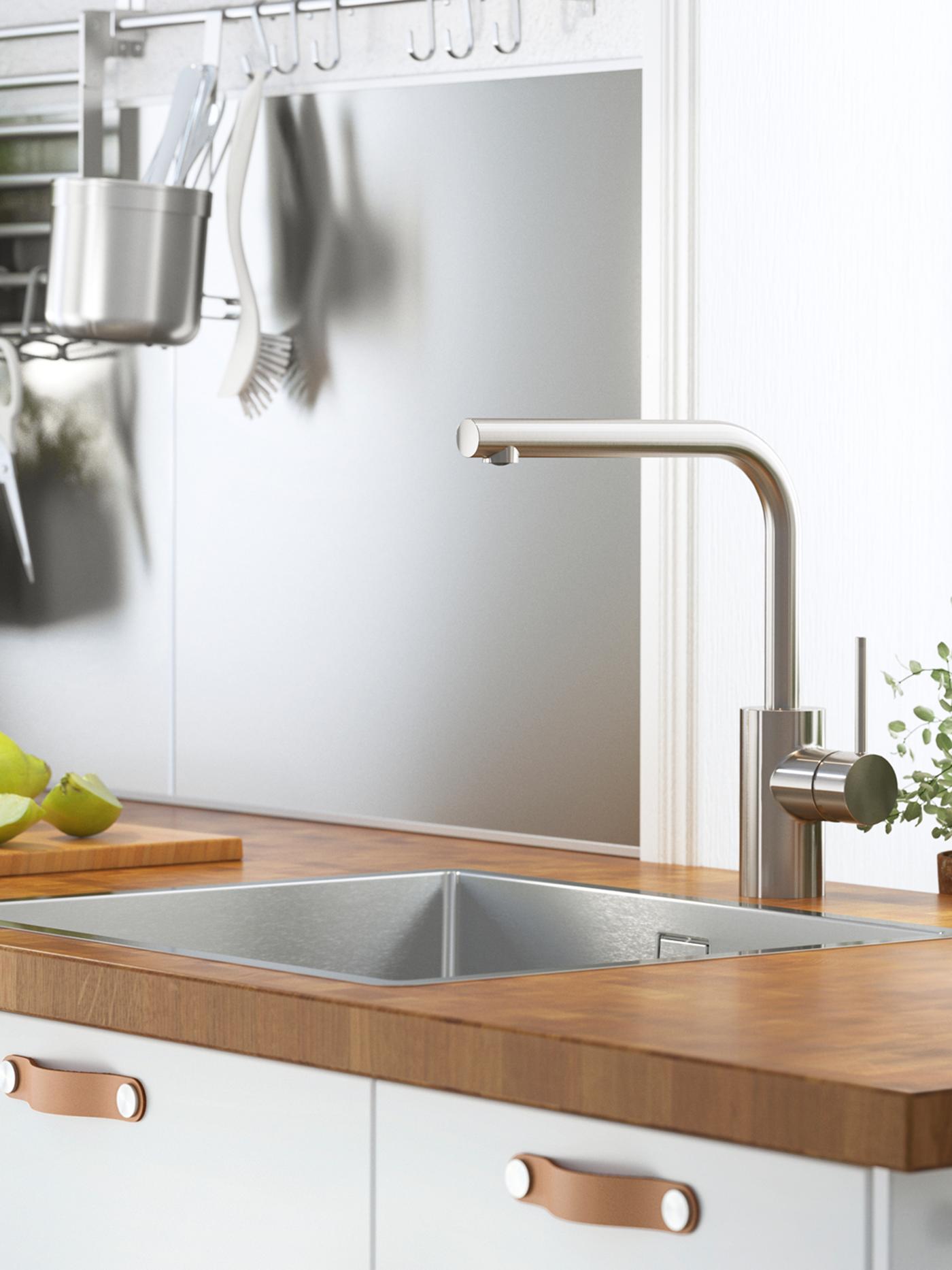 Zidni panel u srebrnoj nijansi, sa šinom, kukama i kuhinjskim priborom okačenim na njega, i sudoperom i slavinom na drvenoj radnoj ploči.