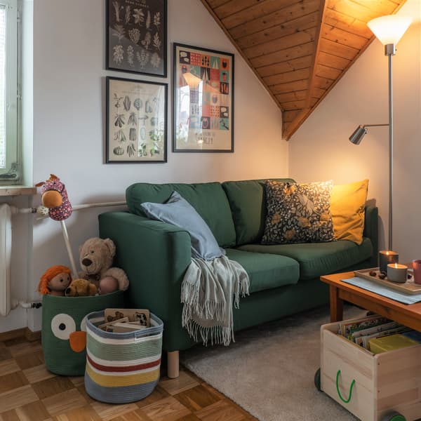 Zielona sofa PÄRUP stojąca w rogu pokoju dziennego.