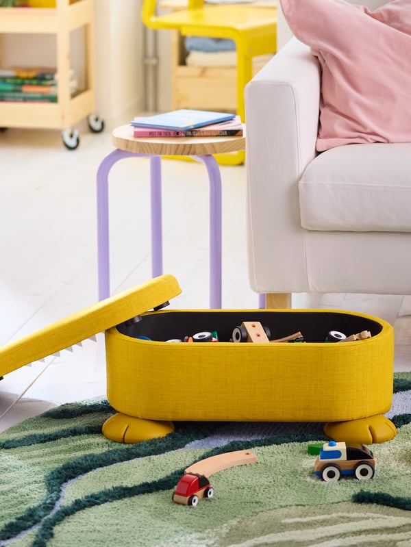 Žlutý taburet GREJSIMOJS na zeleném koberci GREJSIMOJS.