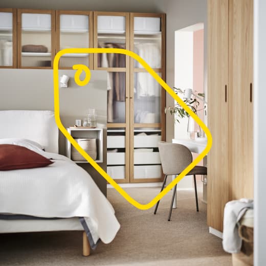 Żółty znak metki znajduje się na zdjęciu sypialni z drewnianą szafą PAX.