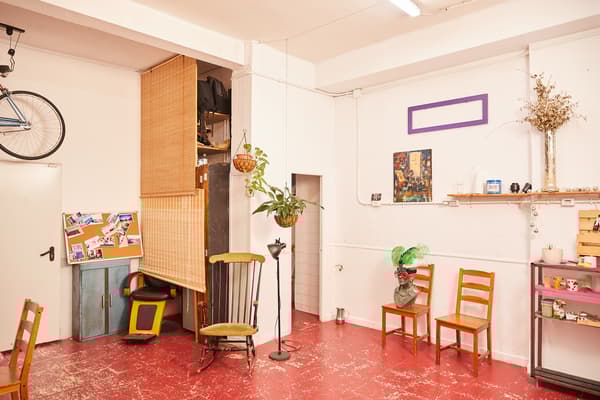 Zona amb nevera, microones, bombona de butà, prestatgeria amb utensilis de cuina, cadires i elements de decoració