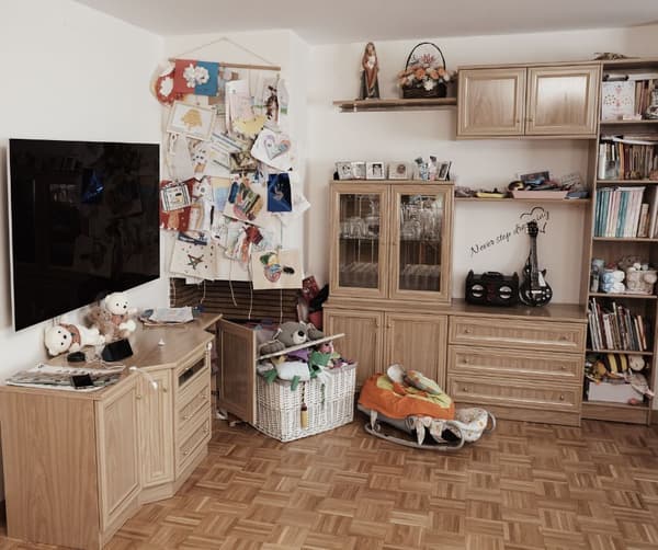 Zona de televisión y juguetes antes de la reforma. Mueble con libros, juguetes y muchos objetos. 