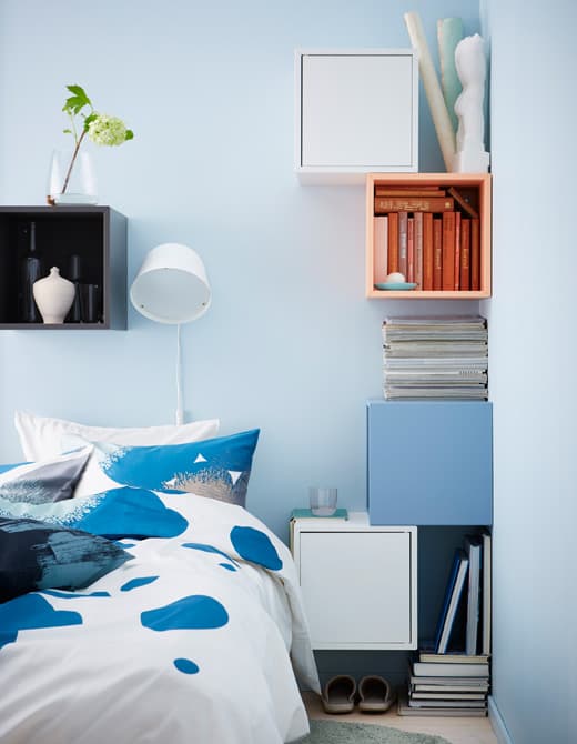 Zrobiony samodzielnie stolik nocny wykonany z kolorowych kwadratowych szafek przymocowanych do ściany wokół łóżka