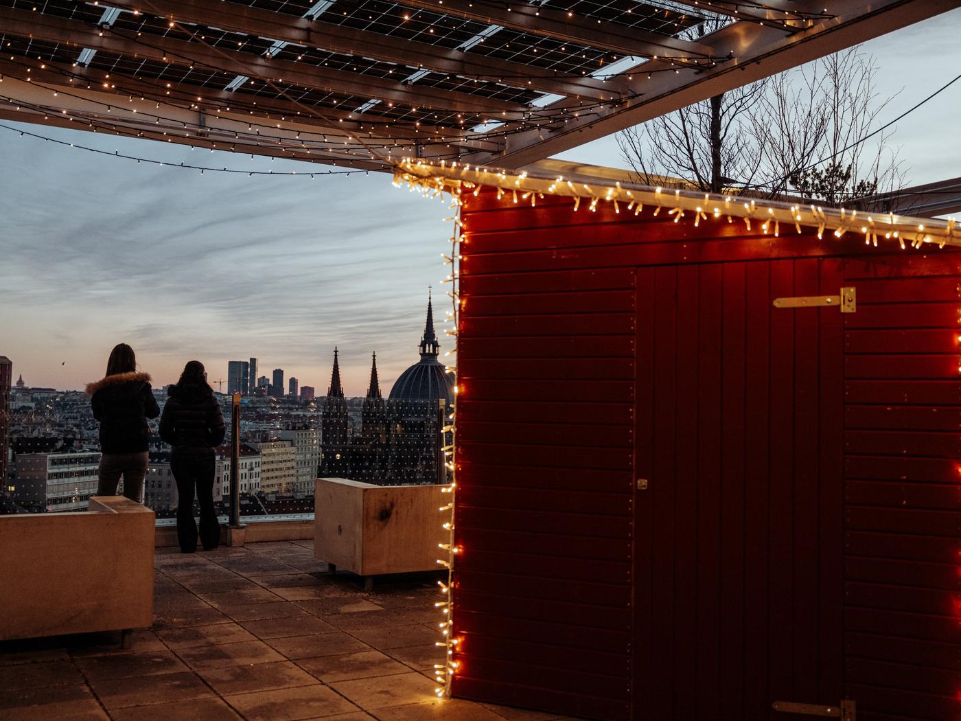 Zu sehen Ausblick von IKEA Wien Westbahnhof Dachterrasse, im Vordergrund sieht man eine rote Punsch-Hütte mit Weihnachtslichtern geschmückt 