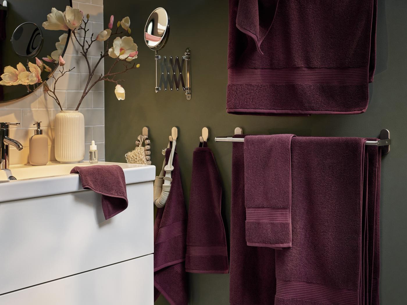 zu sehen ein Badezimmer mit bordeauroten Badtextilien
