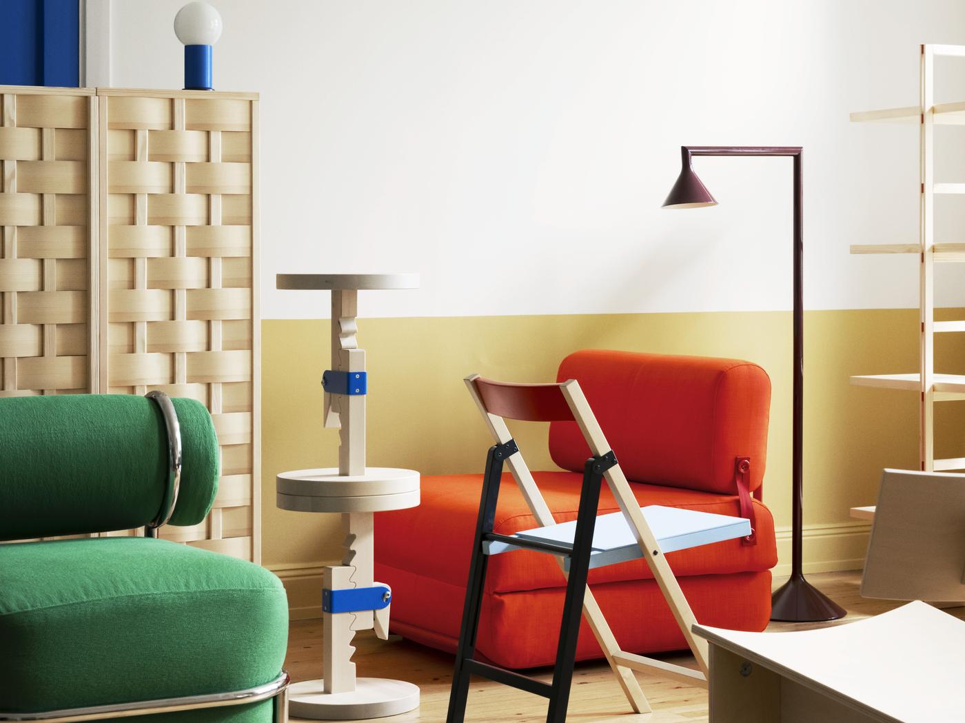 zu sehen eine Zimmerecke, in der 10-12 bunte IKEA Produkte eng zusammengestellt sind, eine Stehlampe, ein rotes Sofa, ein grüner Sessel, ein runder Tisch, ein bunter Sessel..