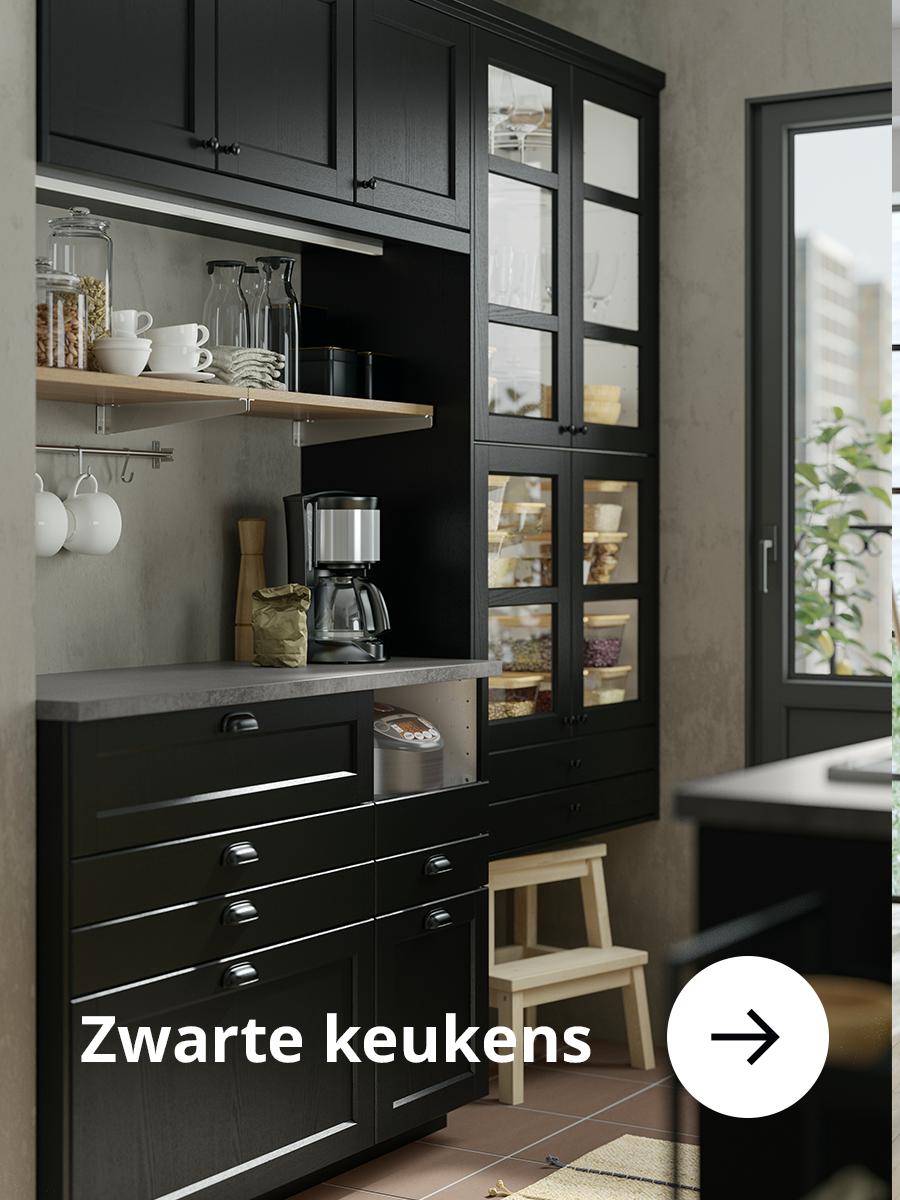 Zwarte keuken met donker aanrechtblad en houten keukentrappetje.