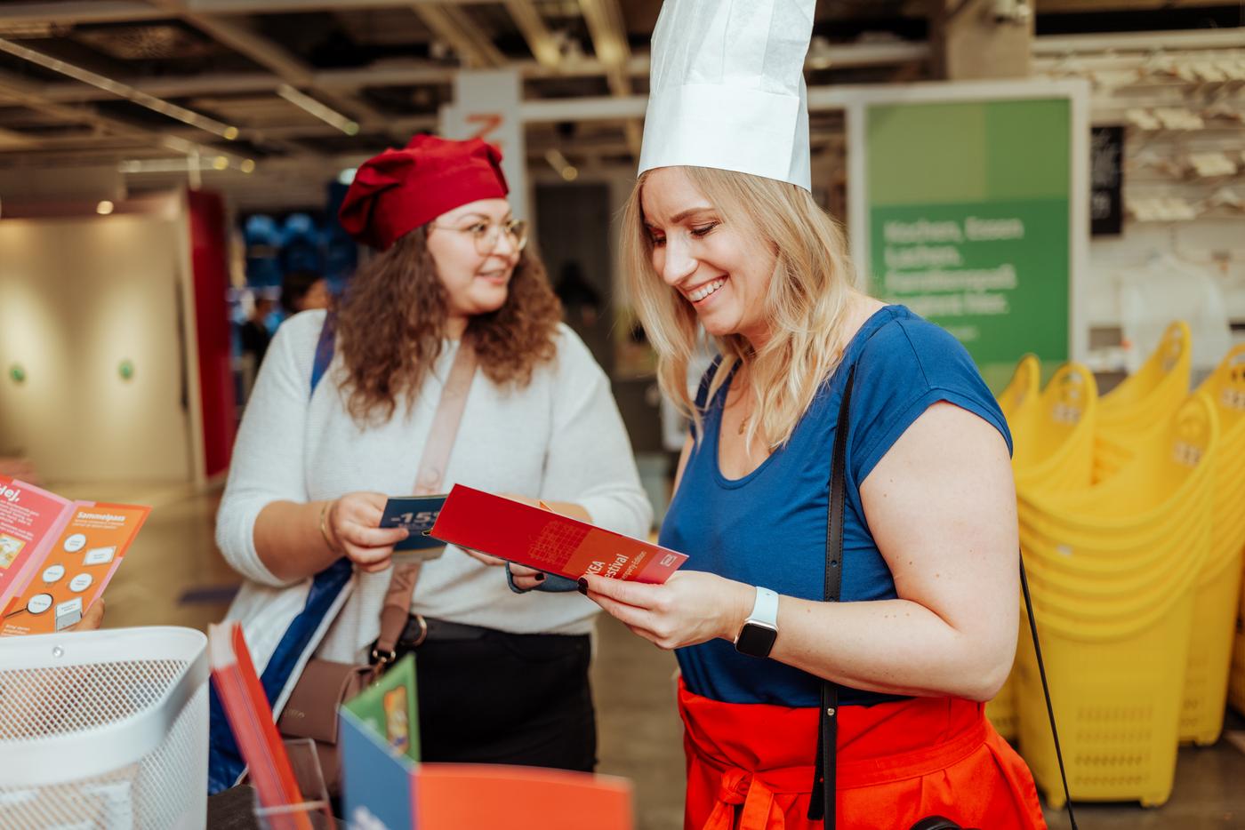 Zwei Besucherinnen nehmen mit Kochmützen an einem Workshop im IKEA Wien Westbahnhof teil.
